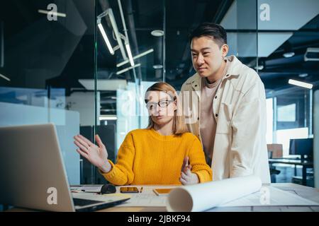 Brainstrom business team is responsible for solving the tasks, employees colleagues Asian man and woman work together in a modern office, look at the Stock Photo