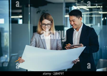 Group young creative engineers Developers discussing new project standing in modern office reading a blueprint. Team thoughtful architect designer. As Stock Photo