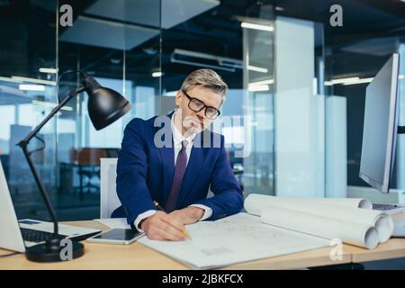 Successful and experienced male designer working in the office on the project, making adjustments to the layout plan Stock Photo