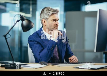 Portrait of a man, businessman thinking while working in the office at the computer Stock Photo