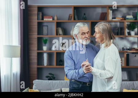 Happy senior couple husband and wife have fun dancing at home, having a good time Stock Photo