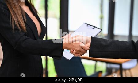 A businesswoman in formal suits shaking hands with her business partner as a welcome, greets or thanks, partnership or congratulations. Cropped and cl Stock Photo