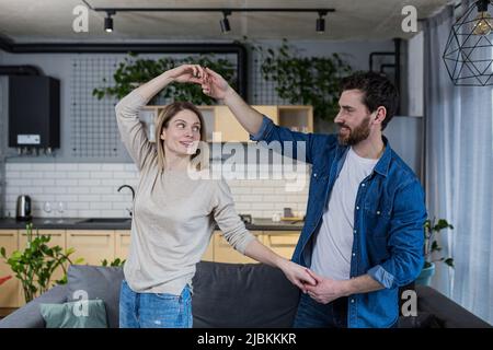 Happy married couple man and woman dancing together at home in the living room, having fun together Stock Photo
