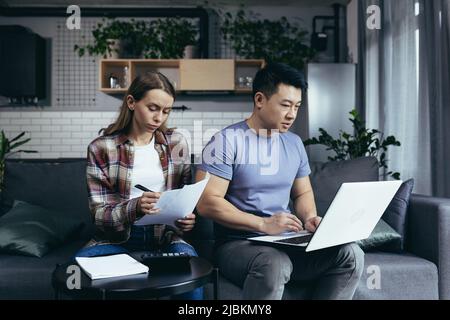 homework, married couple, man and woman, pay bills by laptop, online payments Stock Photo