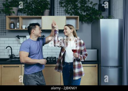 Man and woman dancing together, having fun at home, in the kitchen, a multiracial family Stock Photo