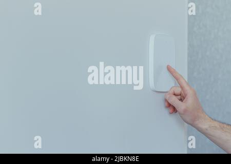Businessman enters finger password lock code on alarm panel, on white wall, rear view of man with beard Stock Photo