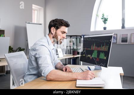 Concentrated and pensive businessman working in the office at the computer, paperwork broker, man looking at the monitor Stock Photo