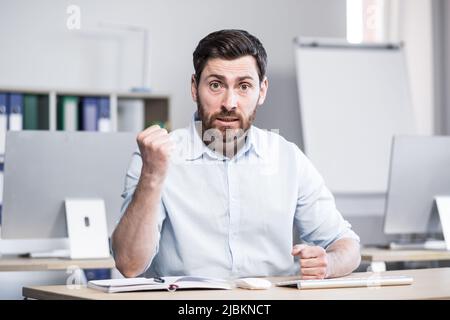 Angry and angry man looking at webcam talking on video call with colleagues online meeting Stock Photo