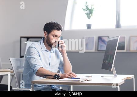 Concentrated and pensive businessman working in the office at the computer, paperwork broker, man looking at the monitor Stock Photo