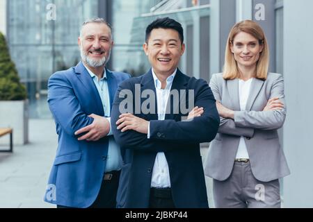 Business team, male and female colleagues in business attire looking at camera and smiling with arms crossed Stock Photo