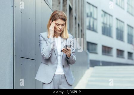 Middle aged business woman, patient has severe headache, businesswoman trying to call doctor using phone Stock Photo