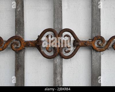 Rusty metal ornament detail on a wooden fence, forming a decorative architectural background texture. Stock Photo