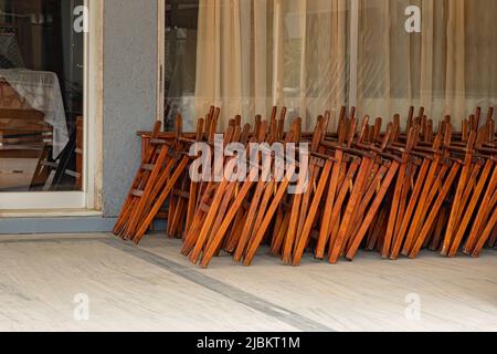 Stacked folding outdoor chairs at the cafe entrance Stock Photo