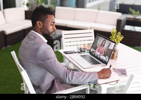 African american businessman planning work while video chatting with businesswoman on laptop Stock Photo