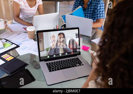 Smiling african american businesswoman waving hand to biracial female colleague on video call. unaltered, business, wireless technology, working, team Stock Photo