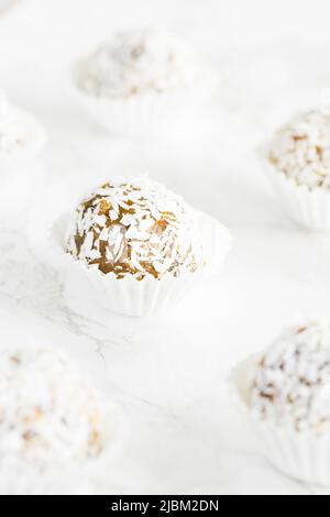 Home made vegan energy protein balls with coconut flakes, almond butter, oats, nuts, dates, dried fruit, flax and hemp seeds served on white backgroun Stock Photo