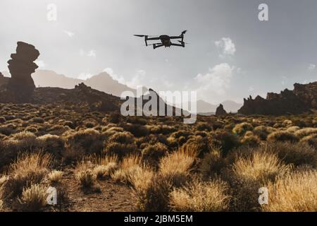 Folding small drone is flying over the mountains. Stock Photo