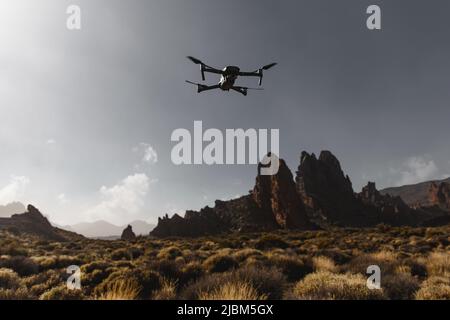 Folding small drone is flying over the mountains. Stock Photo
