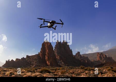 Folding small drone is flying over the mountains. Stock Photo