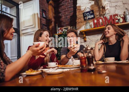 Diverse young people having lunch chatting and smiling in a cafe. Stock Photo