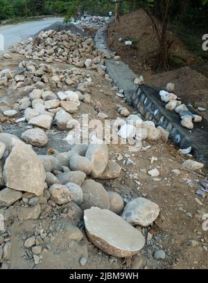A pile of stone alongside the road for constructing a stone retaining wall to prevent landslide and cutting. Uttarakhand India. Stock Photo