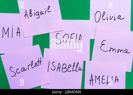 top view of pale purple cards with female names on green background Stock Photo