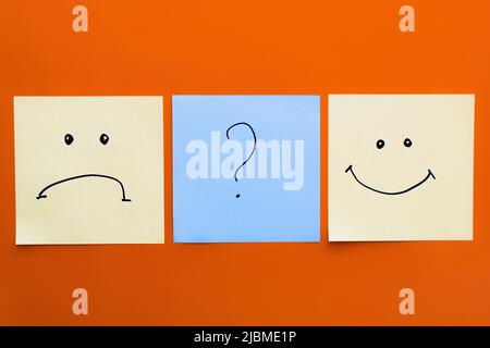 top view of cards with question mark near happy and upset emoticons on red background Stock Photo