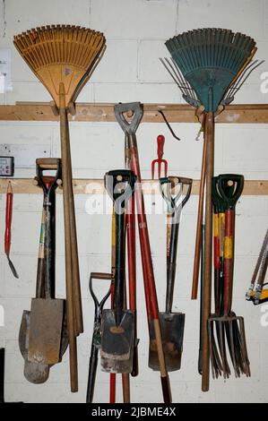 A collection of gardening tools hung on a wall Stock Photo