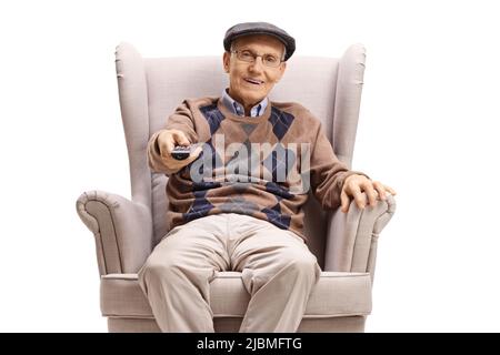 Pensioner sitting in an armchair and using a tv remote control isolated on white background Stock Photo