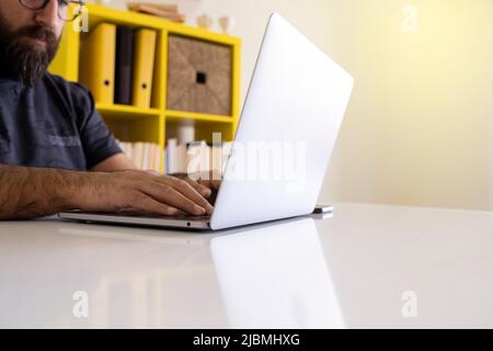 Man using laptop, young bearded hipster man using laptop at his office. Researching and typing his business plan, working focused at modern office. Stock Photo