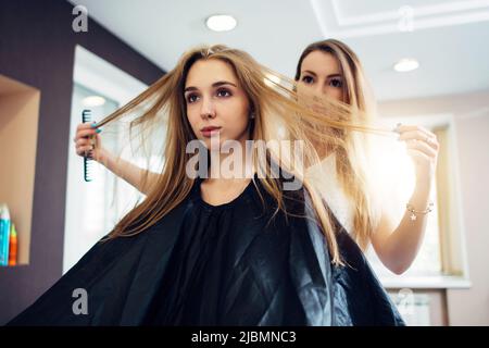 Hairdresser and customer discussing, deciding, choosing how to cut the hair in hairdressing salon. Stock Photo