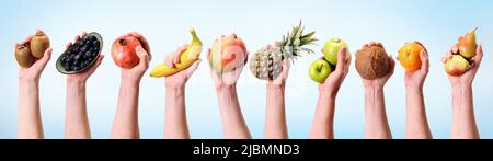 Various hands holding assorted fruits in a banner format.Banana, pineapple, apple and many other hands on diet background. Stock Photo