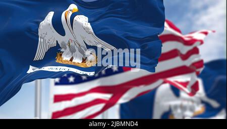 The Louisiana state flag waving along with the national flag of the United States of America. In the background there is a clear sky. Louisiana is a s Stock Photo