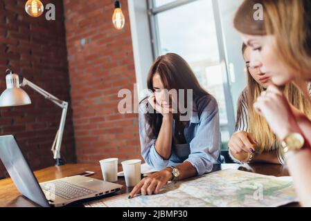Female office workers planning vacation using map. Stock Photo