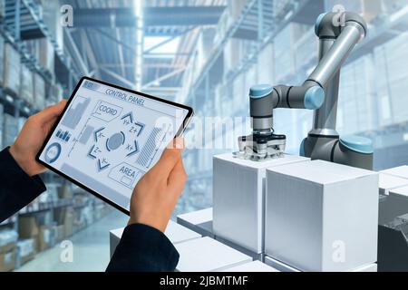 Warehouse manager with digital tablet controls robot arm Stock Photo