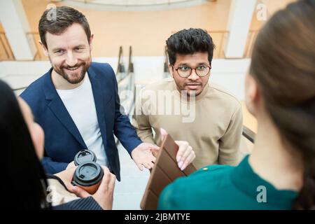 High angle view at diverse business team communicating while standing on escalator Stock Photo