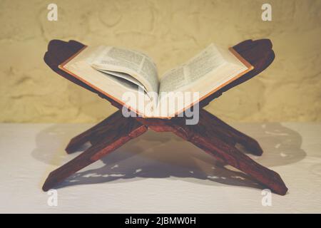 Open Holy Bible on ornate wooden book stand in ascetic setting for meditation and contemplation Stock Photo