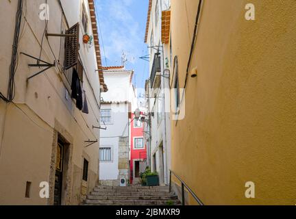 An attractive cobbled street wends it's way between rows of old houses in the centre of Lisbon, capital city of Portugal Stock Photo