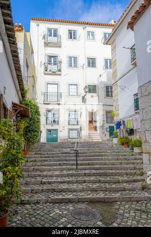 An attractive cobbled street wends it's way between rows of old houses in the centre of Lisbon, capital city of Portugal Stock Photo