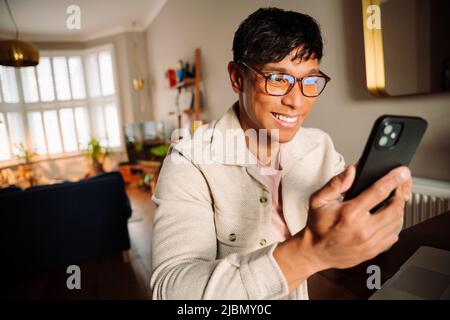Asian man reading funny text on cellular device Stock Photo