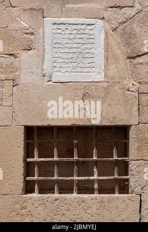 Arabic inscription embossed on a white stone above the window on the facade of the cathedral in Path of the Chaplains, Tortosa, Tarragona, Spain. Stock Photo