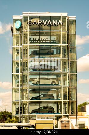 Carvana's glass tower car vending machine filled with vehicles waiting to be picked up from purchasers with brand at the top and partly cloudy sky. Stock Photo