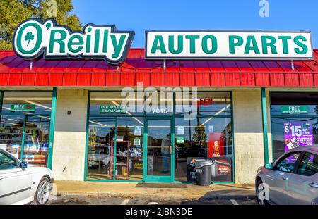 O'Reilly Auto Parts store's exterior facade brand and logo signage in green and white against a red, ribbed roof above a glass window store front. Stock Photo