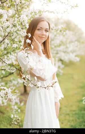 Amazing young woman posing in a garden of flowering trees in spring. Stock Photo