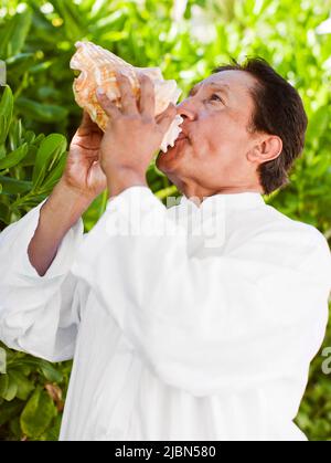 An older Mexican man blows a conch shell at Live Aqua Resort & Spa, a 371-room luxury all-inclusive hotel in Cancun’s Hotel Zone. Cancun, Quintana Roo Stock Photo