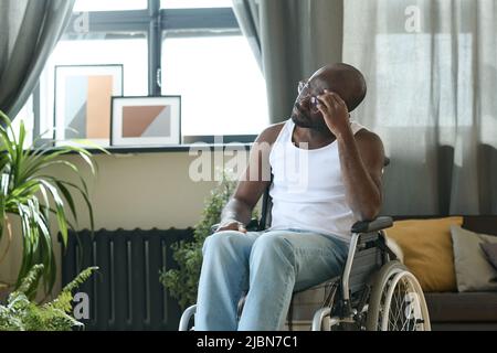 African American man sitting in wheelchair alone in the room and thinking about something Stock Photo