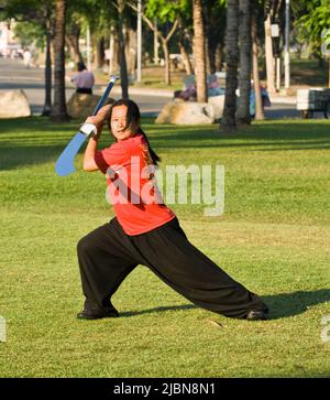 Young Thai woman Tai Chi exercise with a blade sword in Lumpini park, Bangkok, Thailand Stock Photo