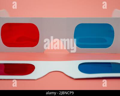 Red and blue paper glasses for viewing 3D movies and images. Isolated on a pink background. Stock Photo