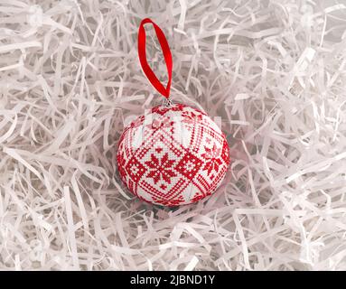 A Cross stitched Christmas ornament on white shredded wrapping paper background. This Christmas ornament made by me. Stock Photo