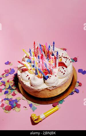 cheesecake with lots of birthday candles and confetti on a pink background Stock Photo